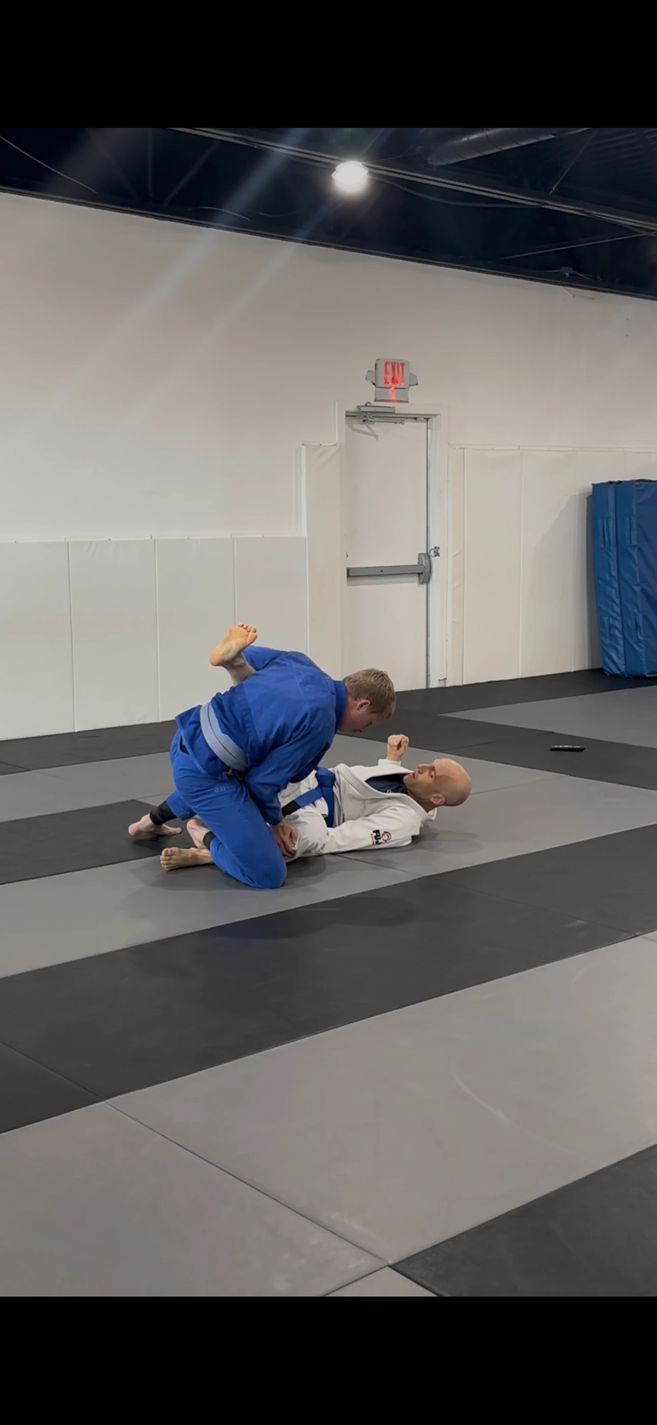 A coach guiding an adult student through a technique in the gi